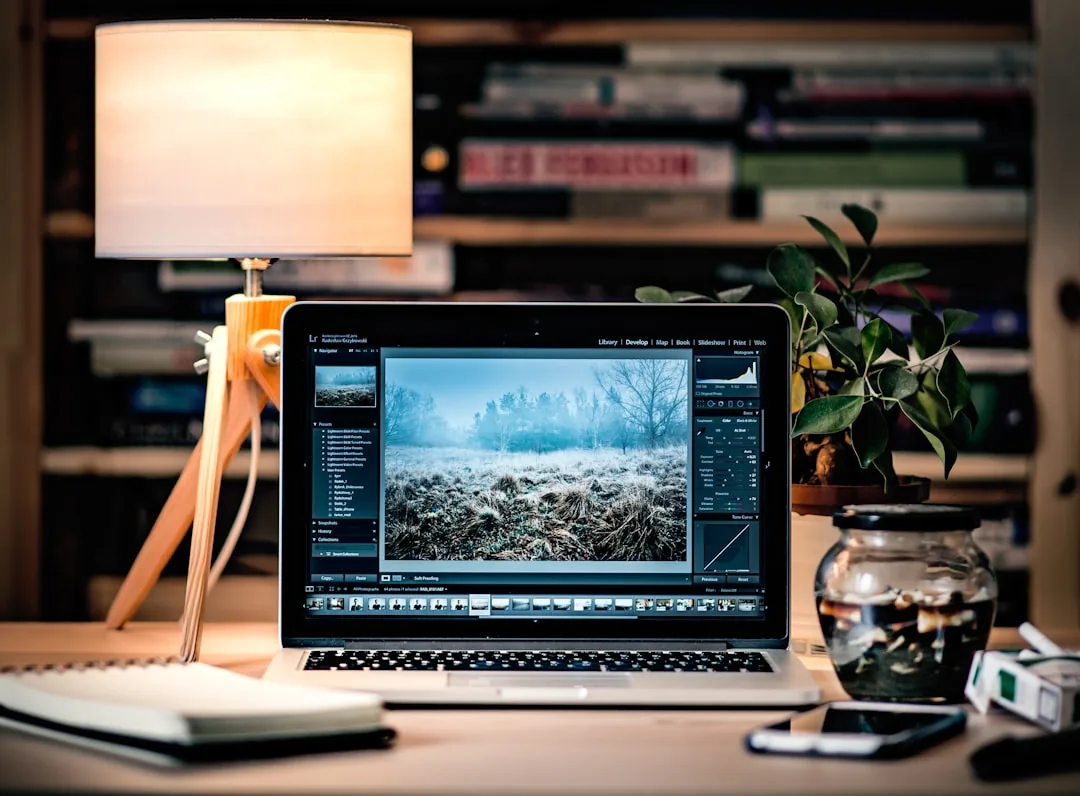 Photographer workspace with MacBook open to a website audit dashboard on a warm wooden desk