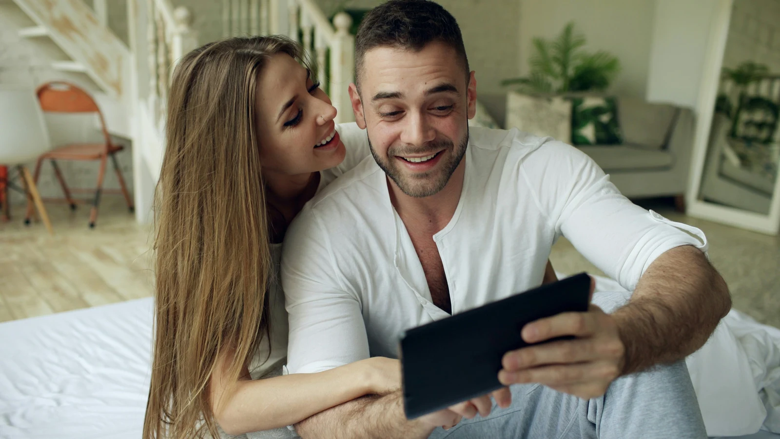 Couple smiling while looking at photos together — happy clients in an in-person sales photography reveal