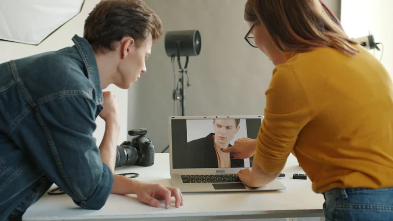 Photographer and client reviewing ad results on laptop in studio