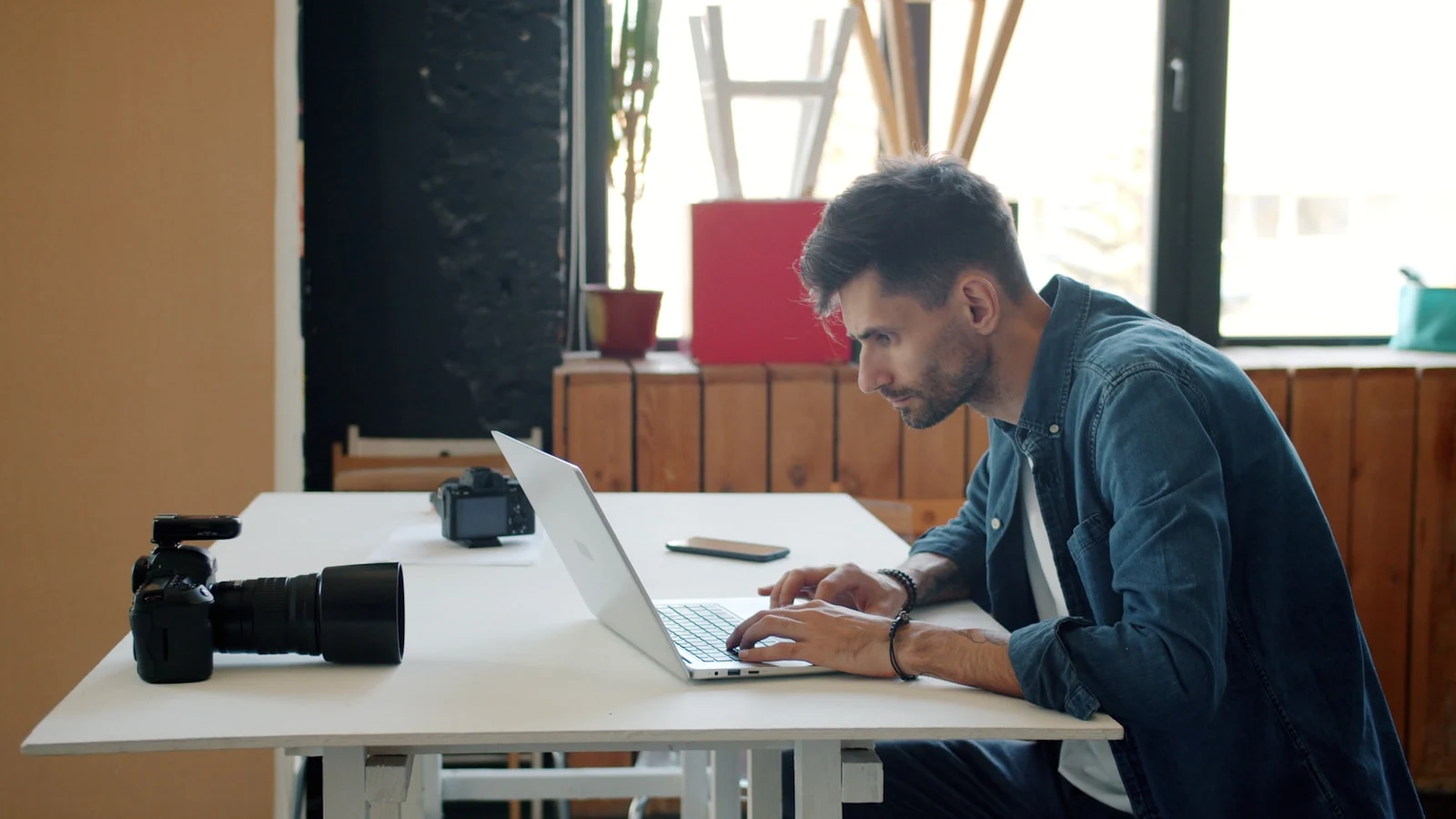 Photographer working at desk with laptop and camera, managing a fully booked studio